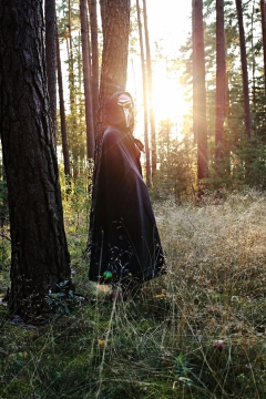 傍晚阳光自然森林戴面具穿黑色长袍女性