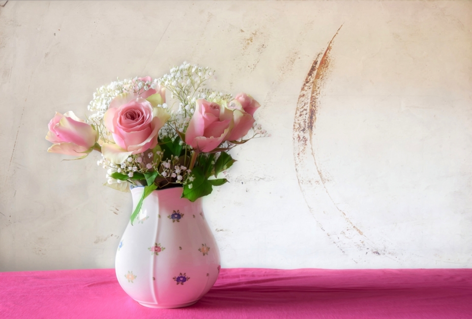 红色桌布上粉色玫瑰装饰白色花瓶