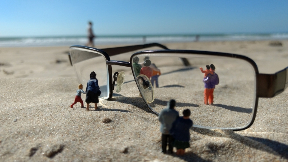 海边沙滩上眼镜和玩具小人的静物微距摄影
