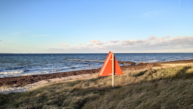海岸边草丛上竖立的警示标志