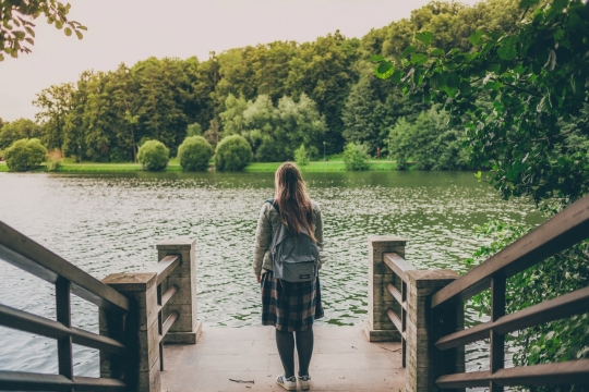 绿色树木环绕的湖边码头少女背影