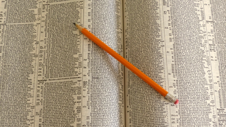 书本泛黄内页上橙色笔杆铅笔