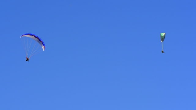 蓝色天空下滑翔这的滑翔伞运动员