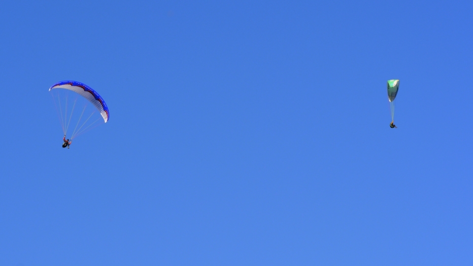 蓝色天空下滑翔这的滑翔伞运动员