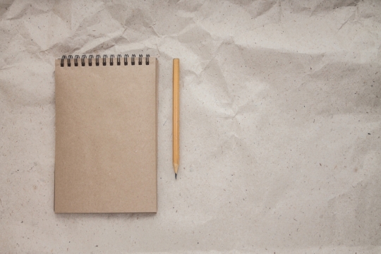 草纸上放着一个记事本和一只铅笔