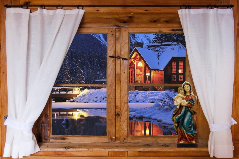 木窗台上圣母雕像和窗外雪地房屋