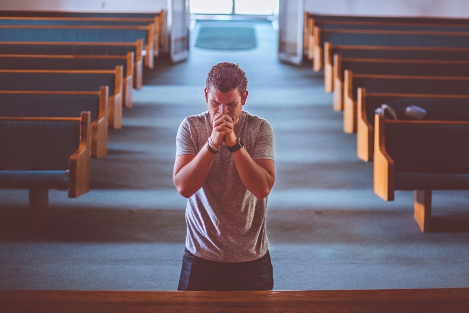 在教堂中双手交错虔诚祈祷的男人