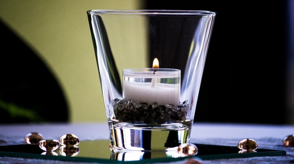 虚化背景室内透明玻璃杯燃烧白色蜡烛