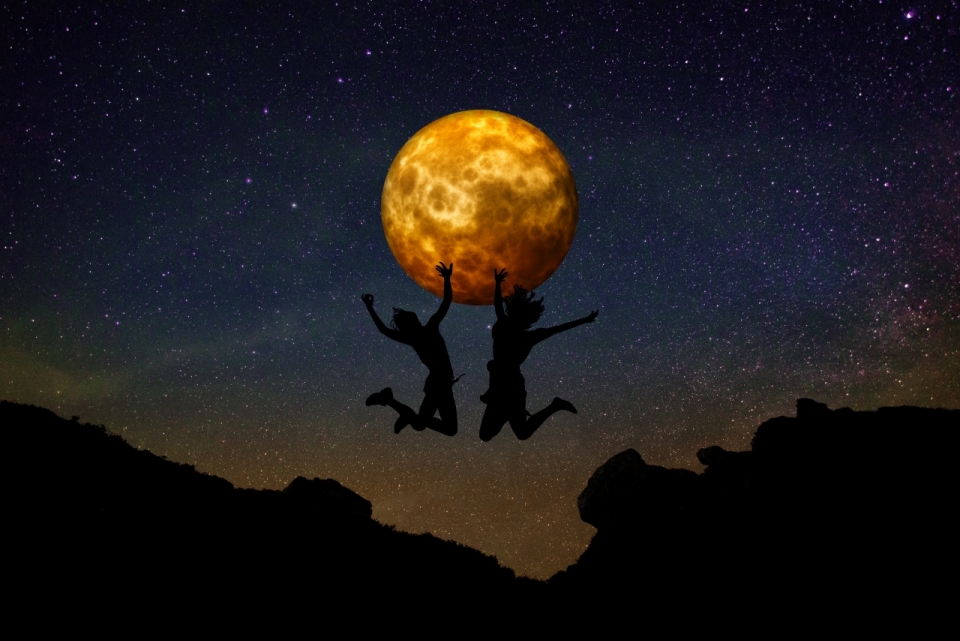星空下跳跃在半空托起月亮的两个人