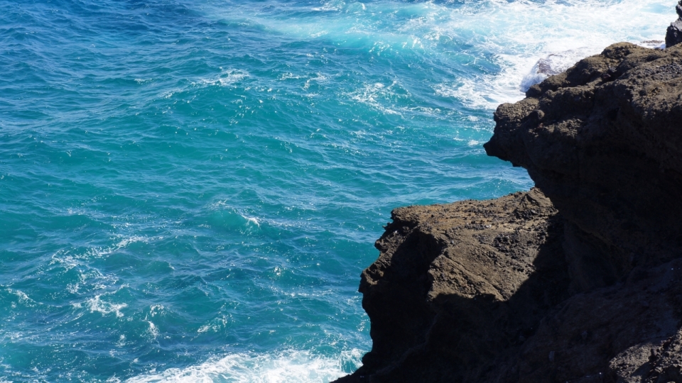 自然岩石边阳光美丽白色浪花蓝色大海