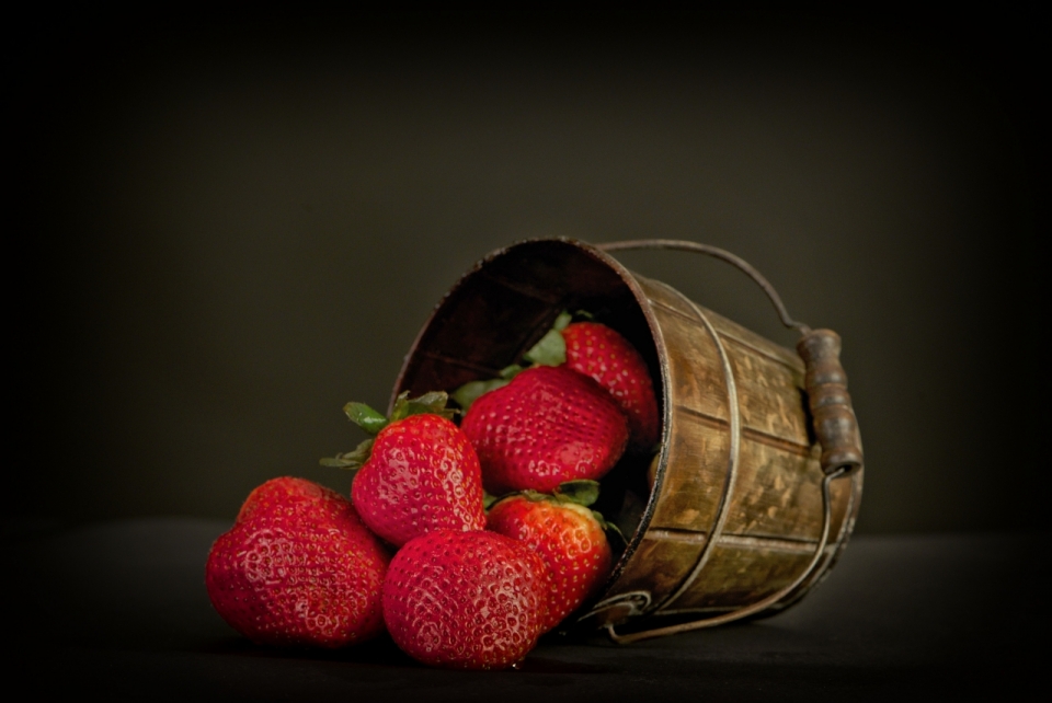 黑色背景木桶倒下洒出来的草莓水果摄影