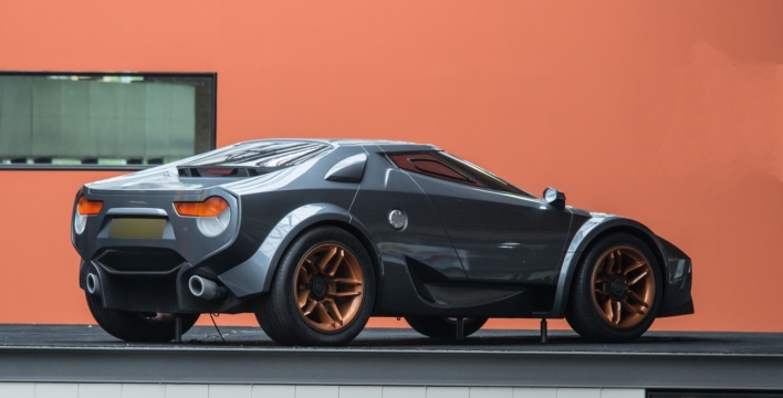 橙色墙壁前崭新黑色豪华轿车