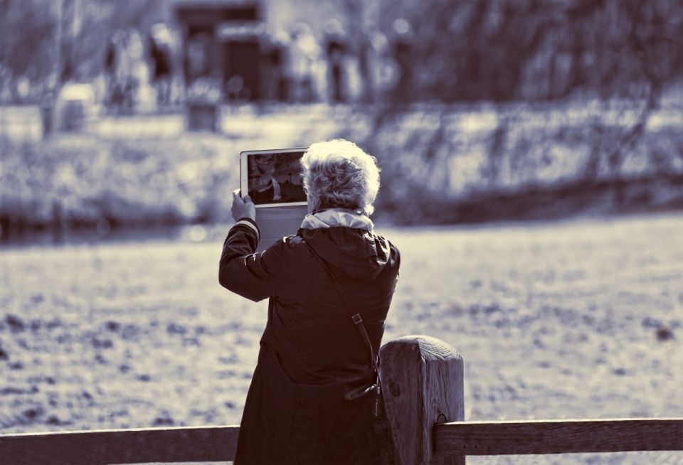 黑白城市街道举iPad老年女性