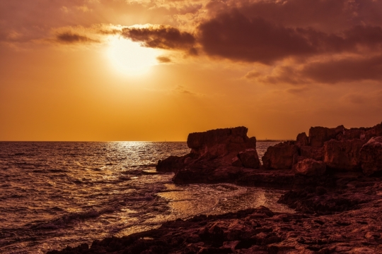 大海上的夕阳照亮整个沙滩和礁石