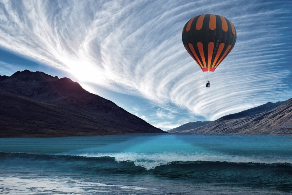 蓝色天空山峰湖泊间彩色热气球