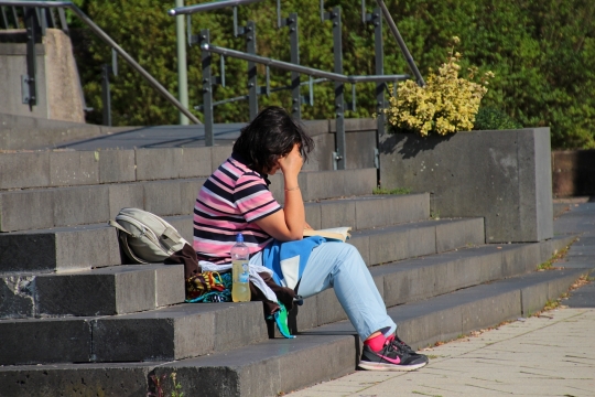 阳光城市街道石阶阅读书本短发女性