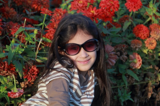 侧躺在花丛中带着太阳眼镜的小女孩特写摄影