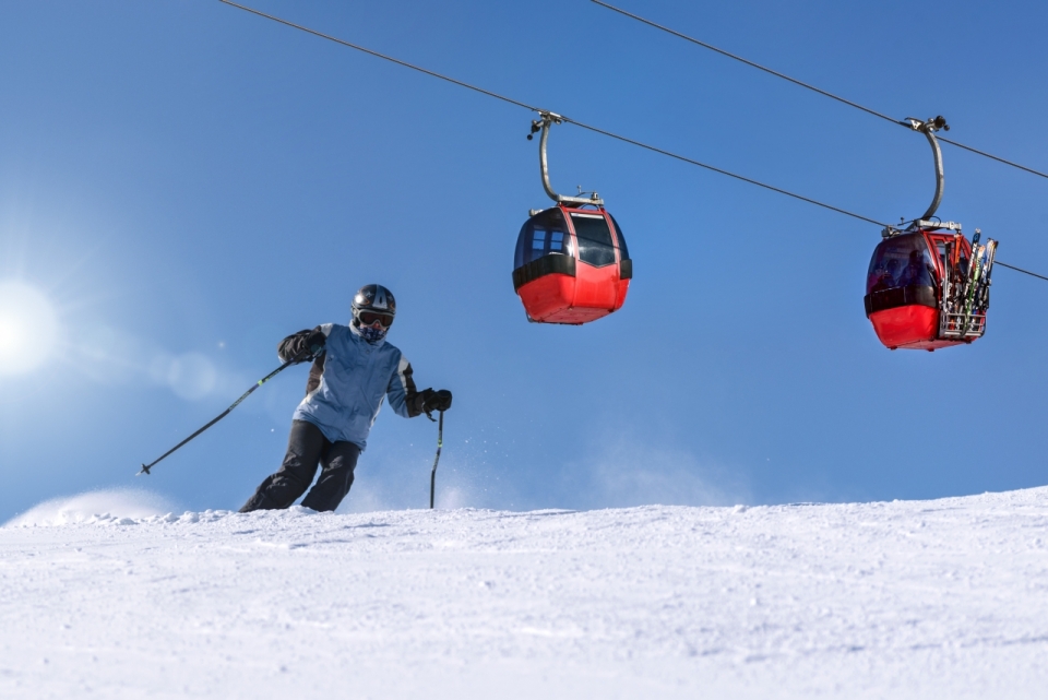 冬天滑雪场运动者上方红色观览车