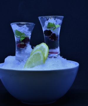 昏暗室内大碗冰块中玻璃杯饮品