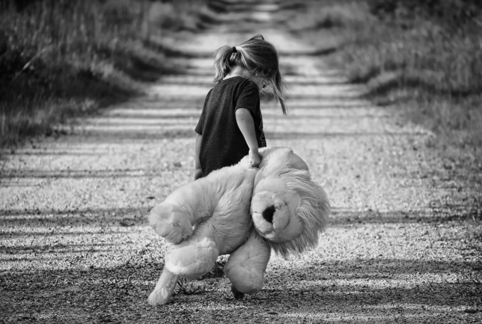 黑白画面小女孩抱着玩具熊独自走在路上