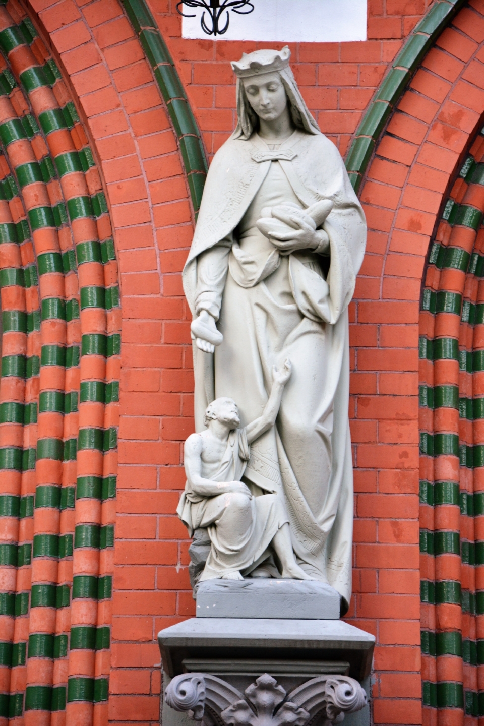 红色砖墙圣母和耶稣的大理石雕像