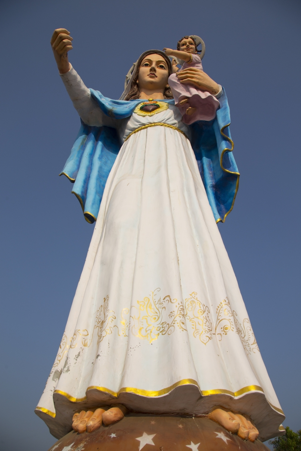 蓝天下彩色圣母玛利亚塑像仰拍