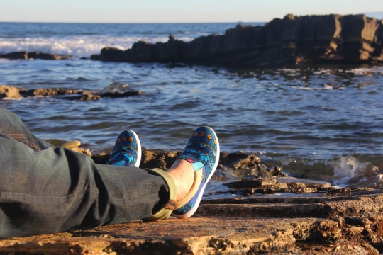 阳光下躺在大海礁石上的男人脚部特写