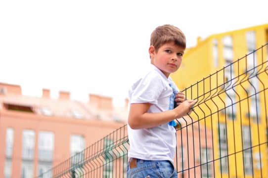 背景虚化房屋建筑围栏旁的男孩