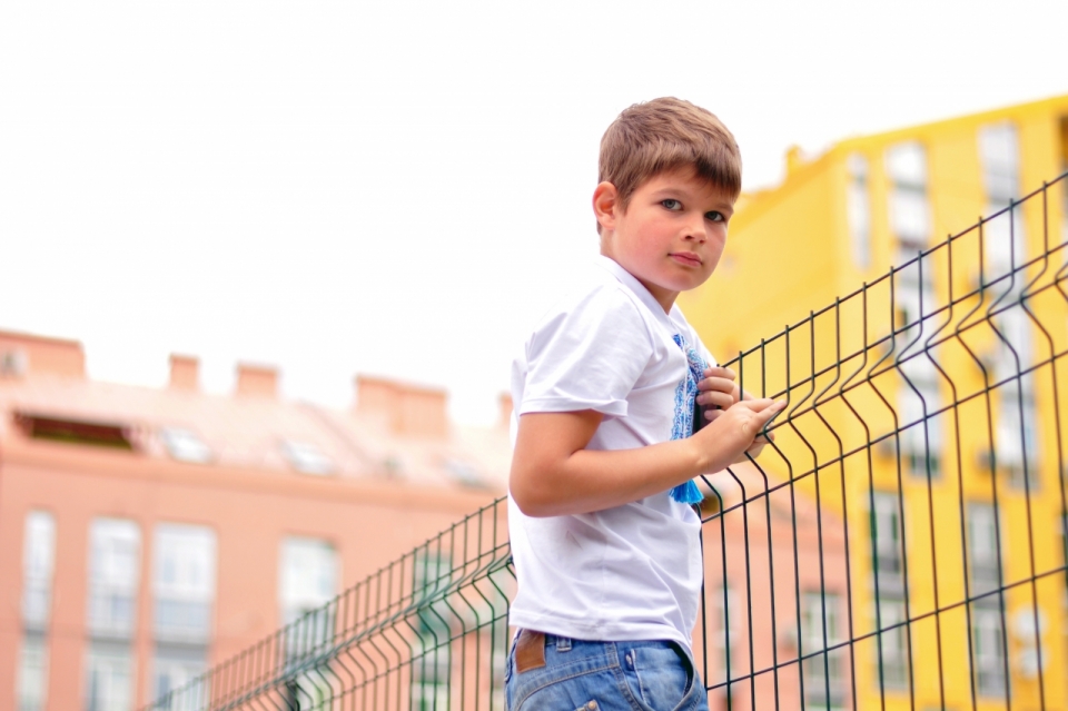 背景虚化房屋建筑围栏旁的男孩