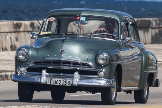 阳光城市街道马路上男性驾驶绿色轿车