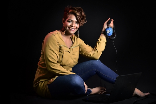 黑色背景坐地面拿蓝色头戴式耳机女性