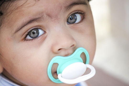 虚化背景室内咬蓝色奶嘴可爱婴儿