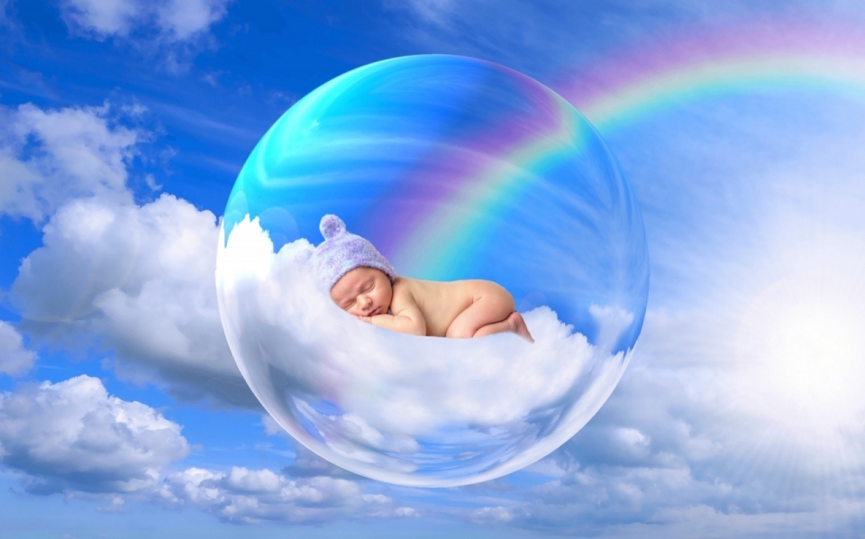 蓝天白云彩虹下气泡中漂浮的熟睡的婴儿