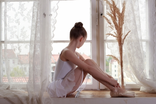 室内窗台前作芭蕾舞蹈准备女孩