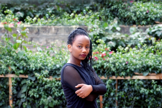 站在花圃边上双手环抱的黑人美女