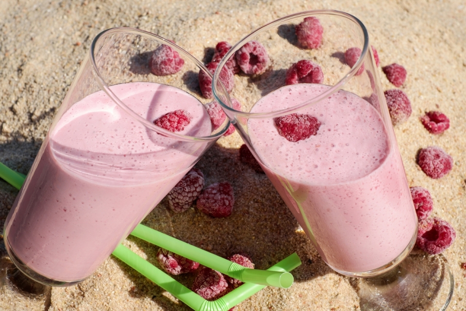 摆在沙滩上的树莓果汁和树莓