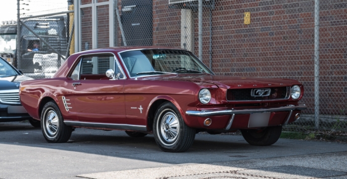 街边建筑阴影遮盖红色轿车外观