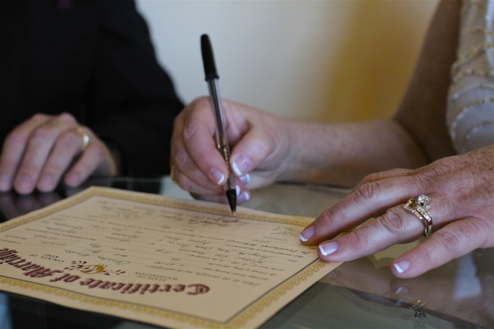 老年女性玻璃桌上用笔签名