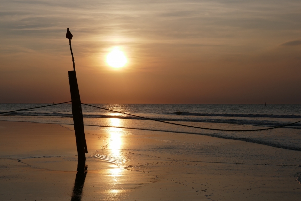 海边沙滩矗立木杆夕阳美景