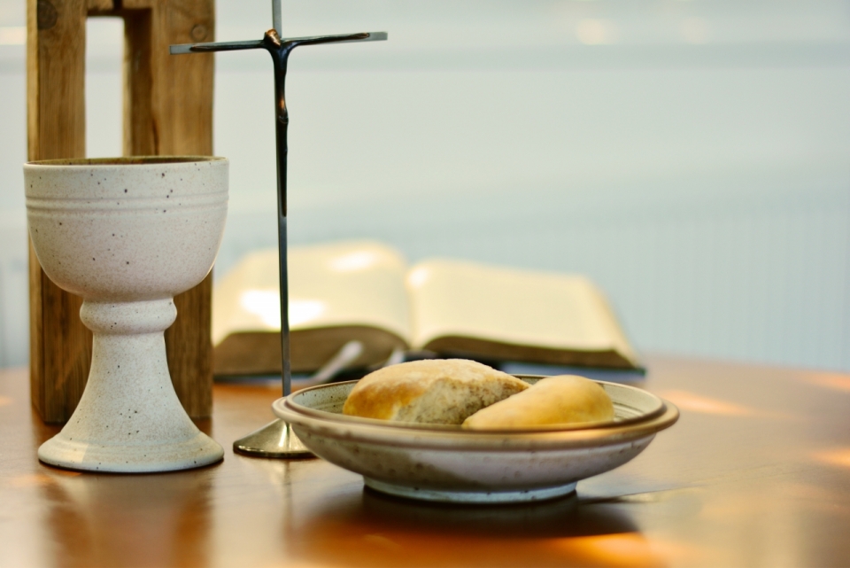 桌面上的十字架圣经杯子与盘子中的些许面包