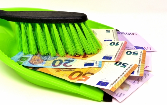 白色桌面绿色簸箕刷子间彩色纸币