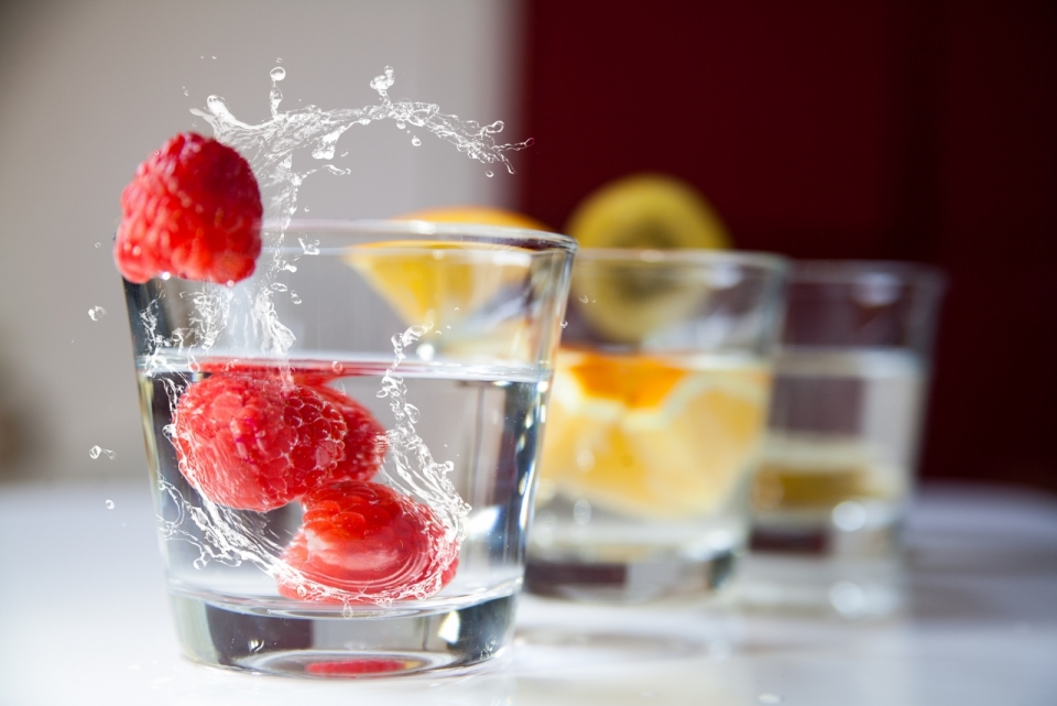 桌上杯子里装着水和不同水果的摄影