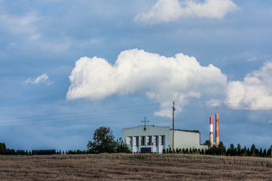 蓝天白云下空旷田野中白色房子建筑和彩色大圆柱烟囱