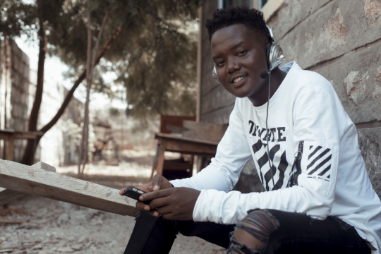 平静午后村庄外戴耳机听歌黑人男孩